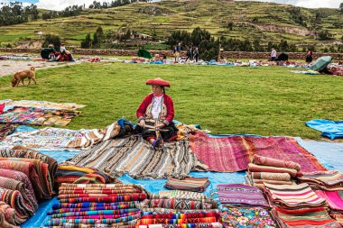 Chinchero, Peru 4 Nisan 2019 Peru 'da Peru tekstil el sanatı satan ve Chinchero, Peru' daki merkez Plaza 'da Alpaca yününden yapılan ürünleri ören kadın..