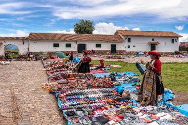 Chinchero, Peru 4 Nisan 2019 Chinchero, Peru 'daki kilisenin önündeki merkez Plaza' da. Geleneksel Peru el işi satan ve Alpaca yününden örgü ören yerli bir kadın.