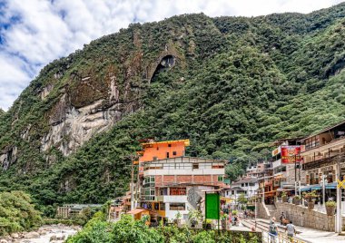 Aguas Caliente, Peru - 8 Nisan 2019: Arkadaki Aguas Caliente şehrindeki evlere, tren yoluna ve Phutuq K 'usi, Putucusi dağına bakın.