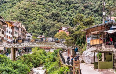 Aguas Caliente, Peru - 8 Nisan 2019: Peru 'nun Aguas Caliente kentindeki ana caddede akan ev köprüleri ve nehir manzarası.