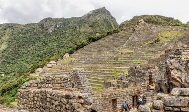 Machu Picchu, Peru - 6 Nisan 2019: Peru 'daki antik İnka kenti Machu Picchu' da evleri ve binaları ziyaret eden turistler. Arka planda Machu Picchu dağı zirvesi.