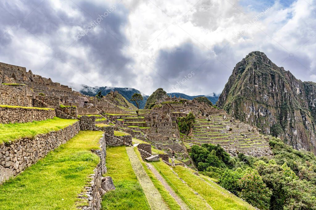 Buildings and houses structures in Incas city of Machu Picchu in Peru. Wayna, Huayna Picchu mountain peak at the background.