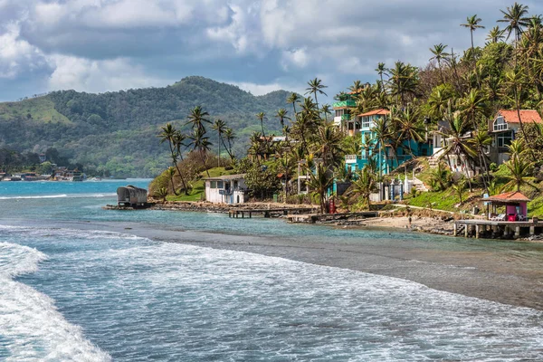 View at Palm trees, sea and houses in Isla Grande shore. Colon province, Panama, Caribbean, Central America.