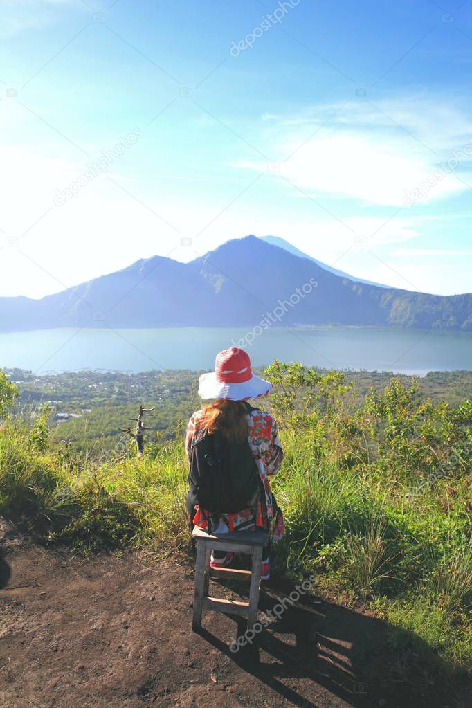 Woman tourist contemplates a mountain lake at the foot of the volcano Batur, Bali, Indonesia