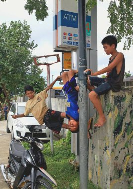 Üç erkek bir motosiklet, Bali, Endonezya yakınındaki çite oynarken