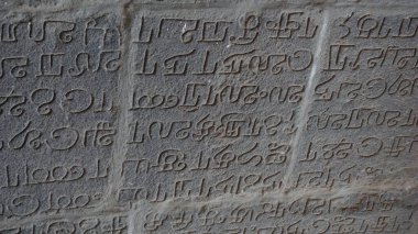 Ancient Indian writings, possibly Sanskrit, which adorn the stone walls of the temple dedicated to God Vishnu in Kanchipur, India clipart