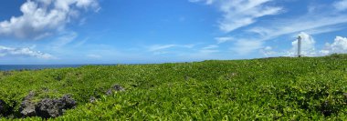 Cape Zanpa deniz fenerinin panoramik manzarası, Okinawa 'da yaz aylarında ferahlatıcı mavi gökyüzü olan bir manzara.