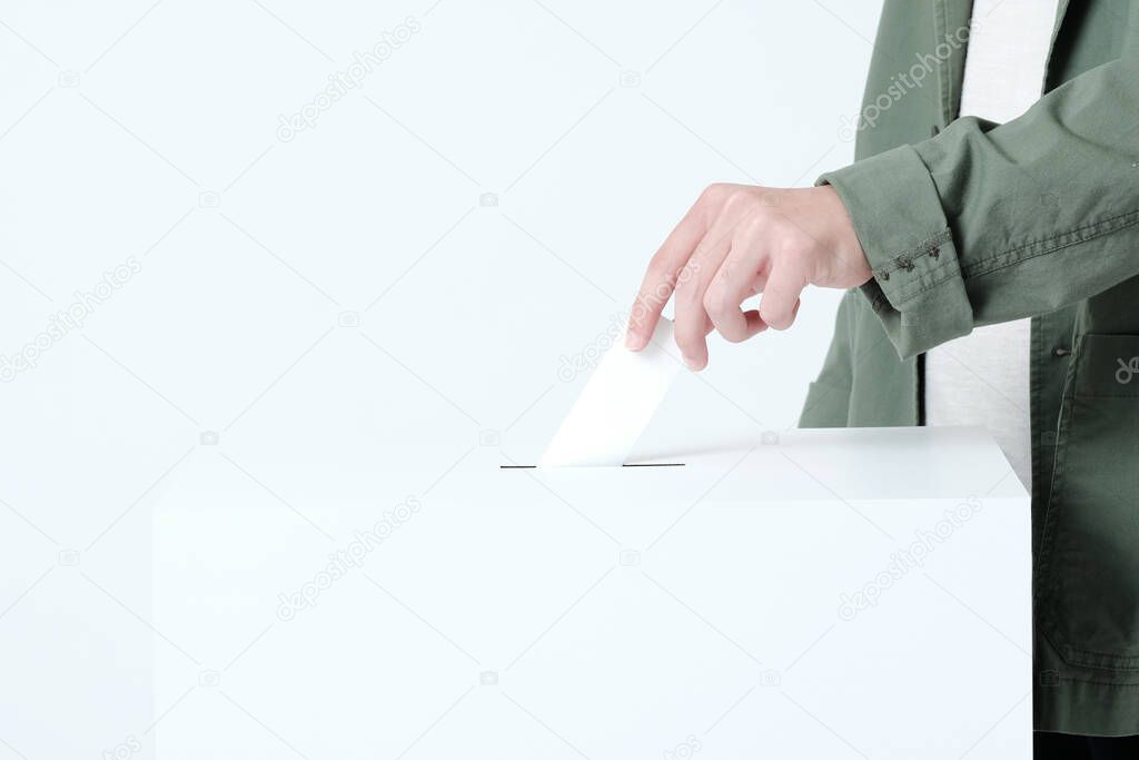 Hands of a young man putting a ballot in an election ballot box