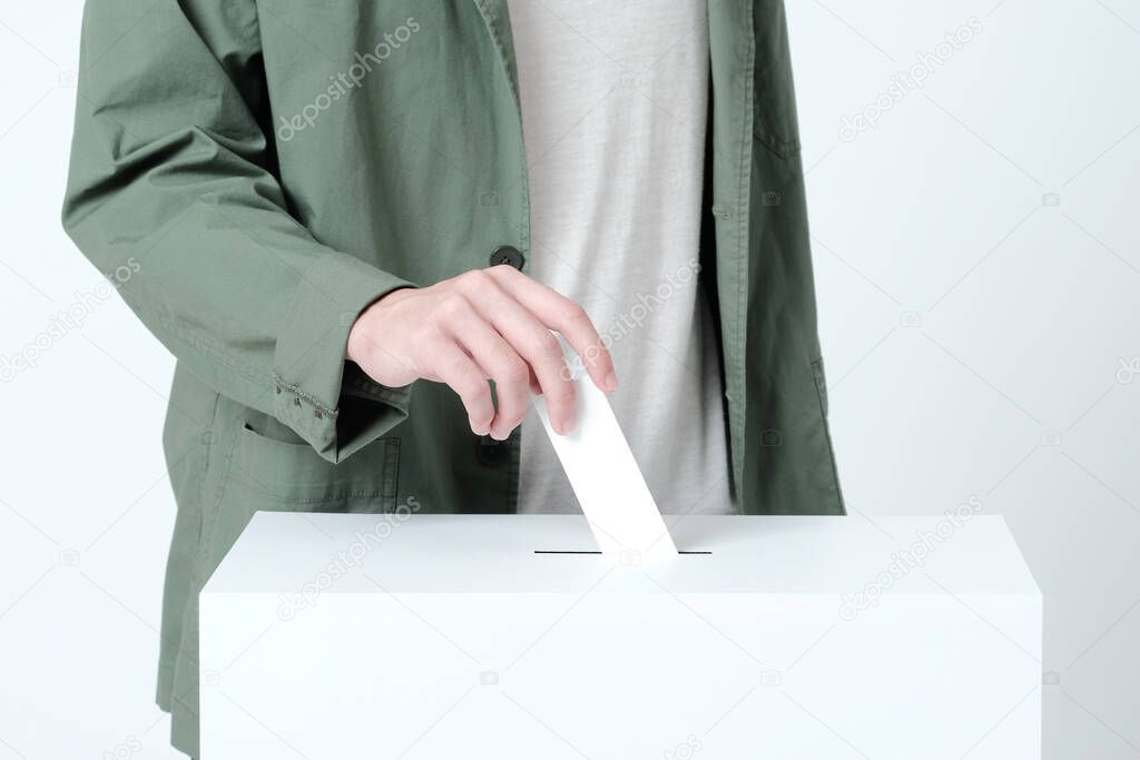 Hands of a young man putting a ballot in an election ballot box