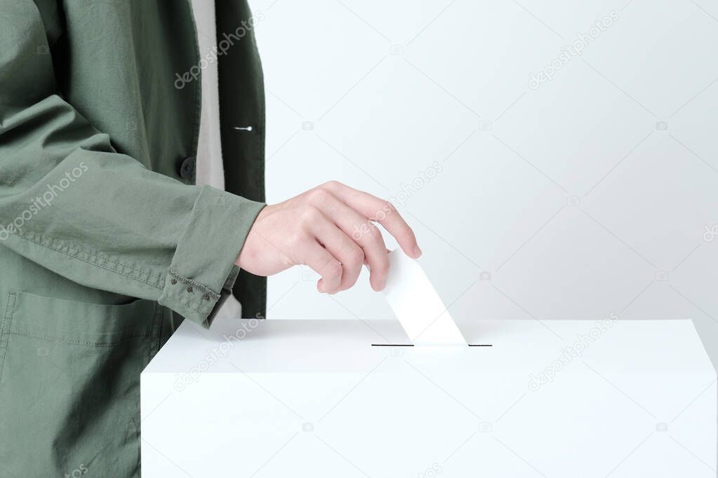 Hands of a young man putting a ballot in an election ballot box