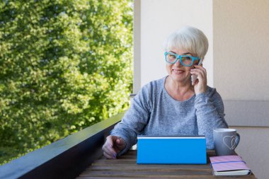 Sarışın saçlı güzel kadın kıdemli bir iş evde çalışır. Teras manzarası. Güneşli gün.