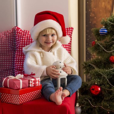 Mutlu bir aile. Bir Noel Baba'nın şapkalı küçük bir kız bir pencere pervazına penceresinde oturur ve saint için bekler.