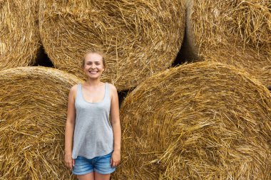 Sarı saçlı bir gülümseyen genç kadınla haymaking arka plan üzerinde duruyor.