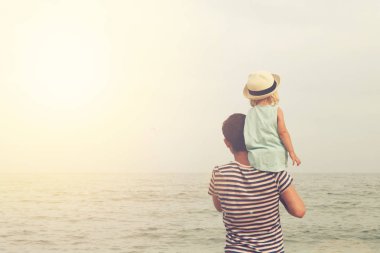 Baba ve kızı plajda durup ve denize bakmak. Arkadan görünüm, kopya alanı.