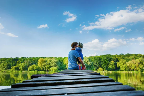 Baba ve kaba pamuklu Tulum içinde küçük bir kız nehirde rahatlayın. Arkadan görünüm, kopya alanı.