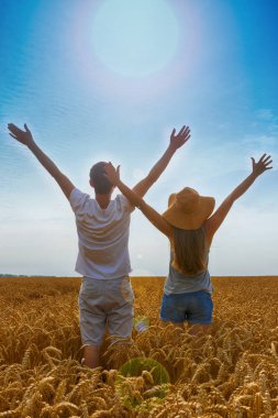 Mutlu bir aile. Kadın ve adam güneşe bakan. Buğday sahada tadını çıkarın. Arkadan görünüm.
