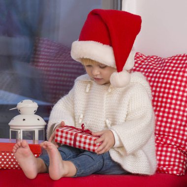 Mutlu bir aile. Bir Noel Baba'nın şapkalı küçük bir kız bir pencere pervazına penceresinde oturur ve saint için bekler.