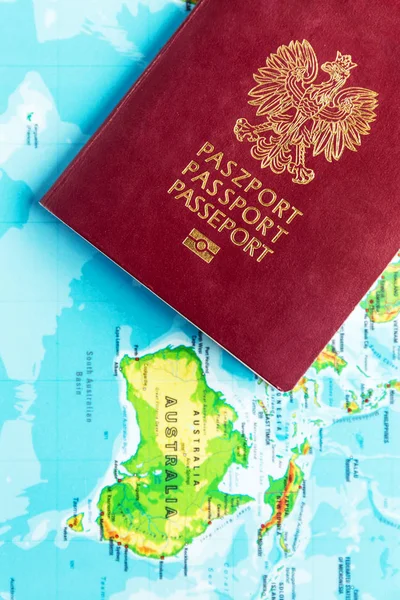 Polish passport of citizen against the continent of Australia. Poles immigration to Australia concept.