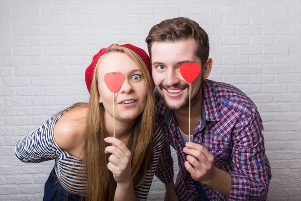 Mutlu bir komik çift aşık Sevgililer günü sahiptir. Sakal ve sarı uzun saçları olan bir kadın olan bir adam. Kağıt kırmızı kalpler. Loft tarzı.
