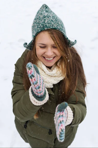 Uzun sarı saçlı güzel bir genç kızla ilk kar sahiptir. Yeşil ceket, yeşil şapka ve eldiven. Üstten görünüm. Kopya alanı.