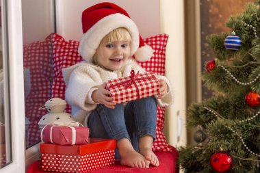 Mutlu bir aile. Bir Noel Baba'nın şapkalı küçük bir kız bir pencere pervazına penceresinde oturur ve saint için bekler.