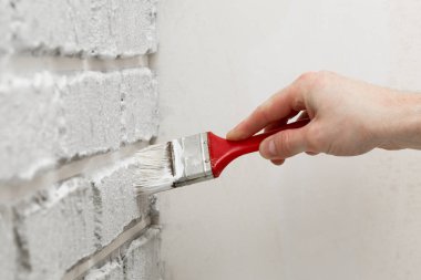 Erkeğin el ile fırça beyaz duvara boyalı. Yenileme çalışmaları. Beyaz arka plan.