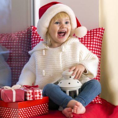 Mutlu bir aile. Bir Noel Baba'nın şapkalı küçük bir kız bir pencere pervazına penceresinde oturur ve saint için bekler.