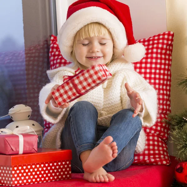 Mutlu bir aile. Bir Noel Baba'nın şapkalı küçük bir kız bir pencere pervazına penceresinde oturur ve saint için bekler.