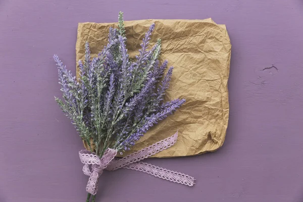 Lavender flower banded ribbon with bow on purple wooden background. Near eco paper.