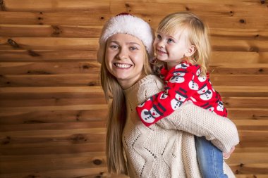 Noel Baba'nın şapkalı küçük kızı olan güzel bir anne Görüntüleyici ve gülümsüyor görünüyor.