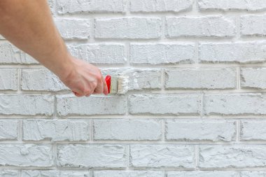 Erkeğin el ile fırça beyaz duvara boyalı. Yenileme çalışmaları. Beyaz arka plan.