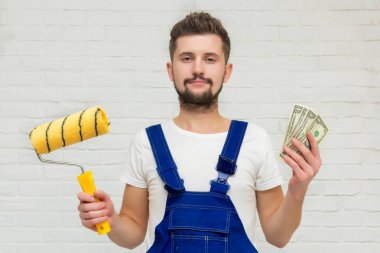 Koyu saçlı Genç adam beyaz daire duvar boyuyor. O bir rulo ve para onun elinde tutar. Ucuz remont kavramı.