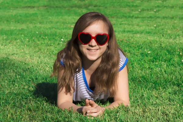 美しい笑顔と都市公園における少女 Spanding 赤いハートのサングラス — ストック写真