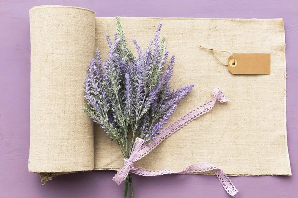 Lavender flower banded ribbon with bow on purple wooden background. Near pease of natural canvas.