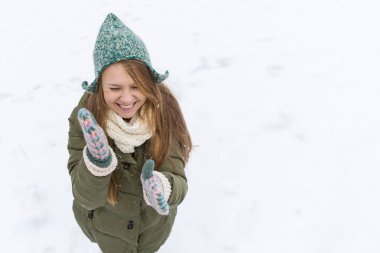 Uzun sarı saçlı güzel bir genç kızla ilk kar sahiptir. Yeşil ceket, yeşil şapka ve eldiven. Üstten görünüm. Kopya alanı.