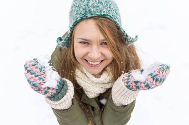 Uzun sarı saçlı güzel bir genç kızla ilk kar sahiptir. Yeşil ceket, yeşil şapka ve eldiven. Üstten görünüm. Kopya alanı.