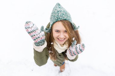 Uzun sarı saçlı güzel bir genç kızla ilk kar sahiptir. Yeşil ceket, yeşil şapka ve eldiven. Üstten görünüm. Kopya alanı.