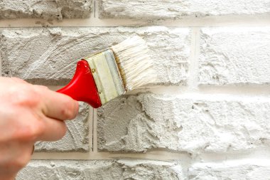 Erkeğin el ile fırça beyaz duvara boyalı. Yenileme çalışmaları. Beyaz arka plan.