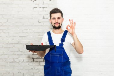 Koyu saçlı Genç adam onun dairesinde beyaz duvar boyuyor. Boya pan elini tutar ve el işaretleri 