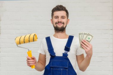 Koyu saçlı Genç adam beyaz daire duvar boyuyor. O bir rulo ve para onun elinde tutar. Ucuz remont kavramı.