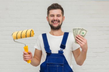 Koyu saçlı Genç adam beyaz daire duvar boyuyor. O bir rulo ve para onun elinde tutar. Ucuz remont kavramı.