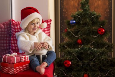 Mutlu bir aile. Bir Noel Baba'nın şapkalı küçük bir kız bir pencere pervazına penceresinde oturur ve saint için bekler.