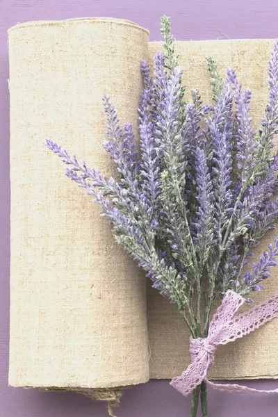 Lavender flower banded ribbon with bow on purple wooden background. Near pease of natural canvas.