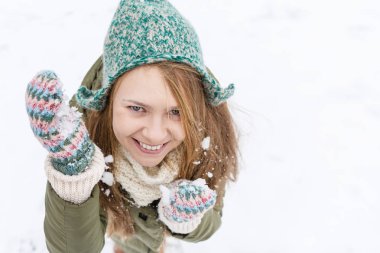 Uzun sarı saçlı güzel bir genç kızla ilk kar sahiptir. Yeşil ceket, yeşil şapka ve eldiven. Üstten görünüm. Kopya alanı.