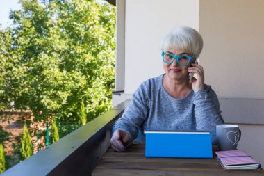 Sarışın saçlı güzel kadın kıdemli bir iş evde çalışır. Teras manzarası. Güneşli gün.