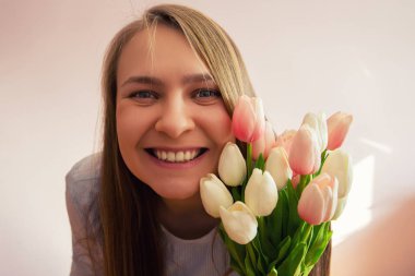 Sarışın uzun bağsız kıl, güzel bir genç kızla bahar çiçekleri güneşli bir gün elinde tutar. O gülümsüyor. Kopya alanı.