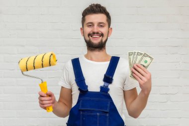 Koyu saçlı Genç adam beyaz daire duvar boyuyor. O bir rulo ve para onun elinde tutar. Ucuz remont kavramı.