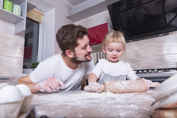 Fathers day! A tiny sweet girl with blond hair spends time with her dad, cooking in the kitchen. Preparations for the holidays. Baking.