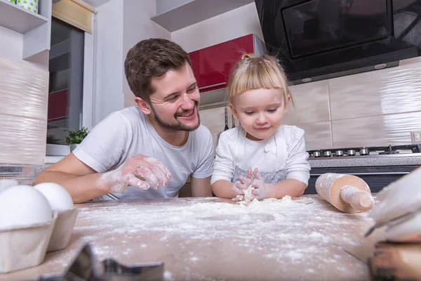 Fathers day! A tiny sweet girl with blond hair spends time with her dad, cooking in the kitchen. Preparations for the holidays. Baking.