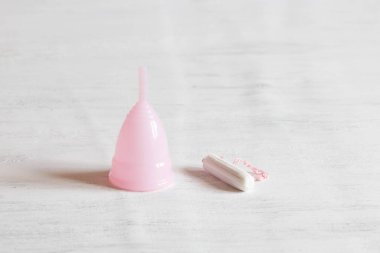 Ne seçerseniz seçin: bir tampon veya adet fincan? Beyaz vintage arka plan. Seçici odak, gün ışığı. 